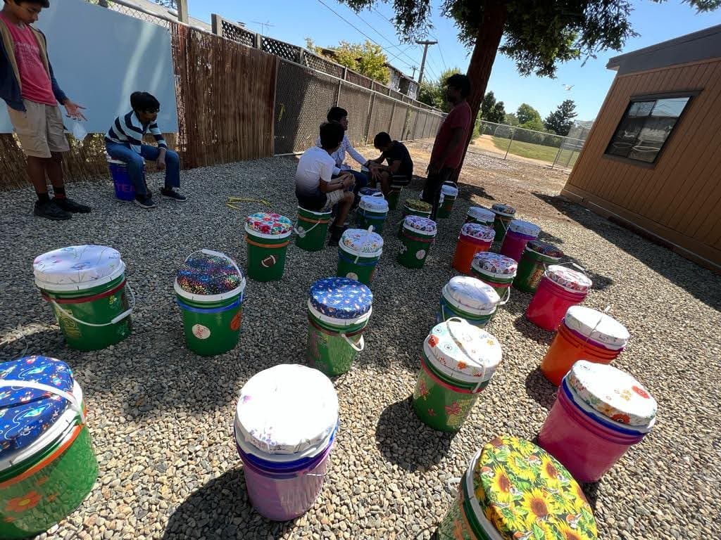 Students at a hands-on session in the Oliveira outdoor classroom, seated on hand-painted bucket seats